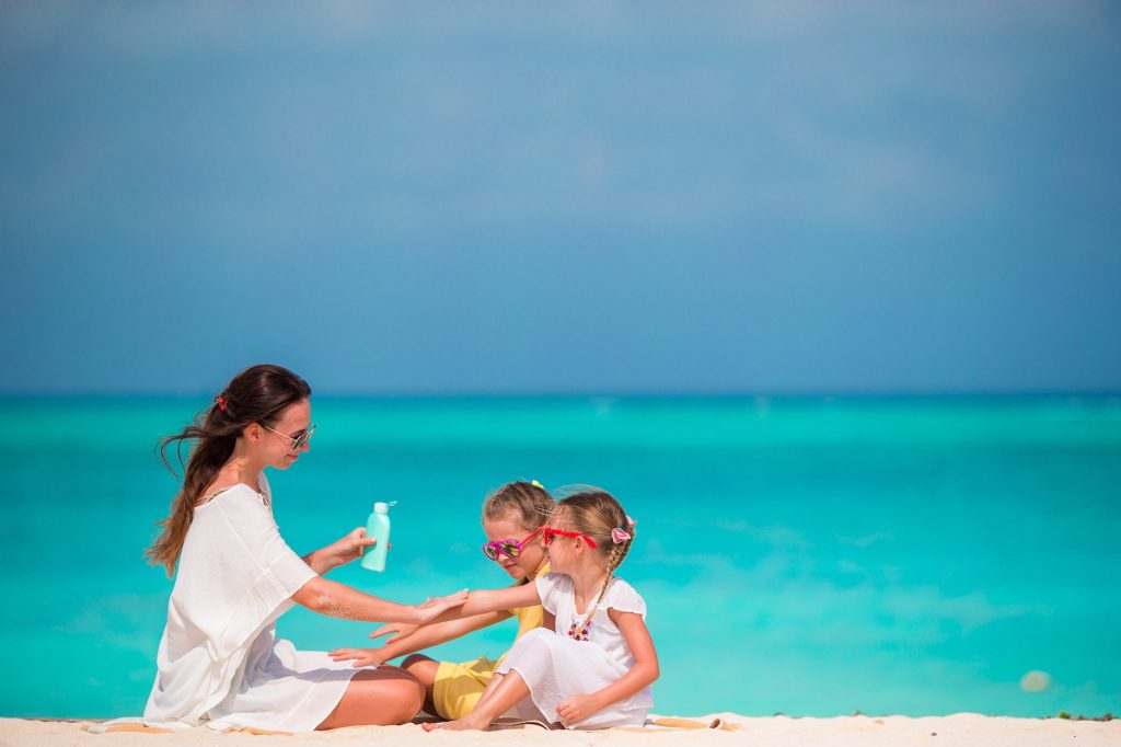 Young mother applying sunscreen on her kids